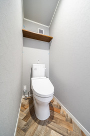 温かみのある空間のトイレ。買い置きのペーパーなども置ける棚も設置されて、便利です。・トイレ便器TOTO「CS340」フチなしトルネード洗浄手洗付便座TOTO「ウォシュレットJS」：ホワイト・トイレカウンターEIDAI「ニューサイクルウッド」：ショコラブラウン・壁クロストキワ「TS-508」・床材フロアシートサンゲツ「CM-10242」