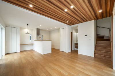 【3号棟リビング】木目柄の天井が心地よい温もりを与えながら、空間に広がりをもたらすLDK。勾配や素材の変化が奥行きを感じさせ、上質で居心地の良いリビングシーンを演出します。