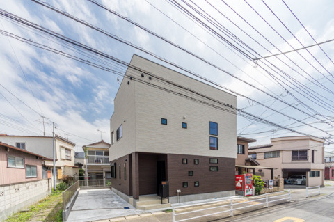 ホワイトとブラウンの外壁材を使ったモダンなデザインの外観。・外壁材：（ベース）旭トステムAT-WALL15PFシュクールP（シュクールホワイトＰ）（アクセント）旭トステムAT-WALL15PFウッドライン16P（ラインダークブラウンP）