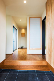 框に腰かけて靴を履いたり、脱いだりできるユニバーサルデザインの玄関。なぐりの壁飾りも木目のやさしい雰囲気を演出！！・床材：LIXIL「アンビストレート300角」（IPF-300/AS-12)・玄関框・付框：ウッドテック（ブラックチェリー）