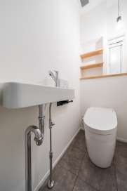 手洗いや買い置きのペーパーなども収納できる棚が設置されたトイレ。